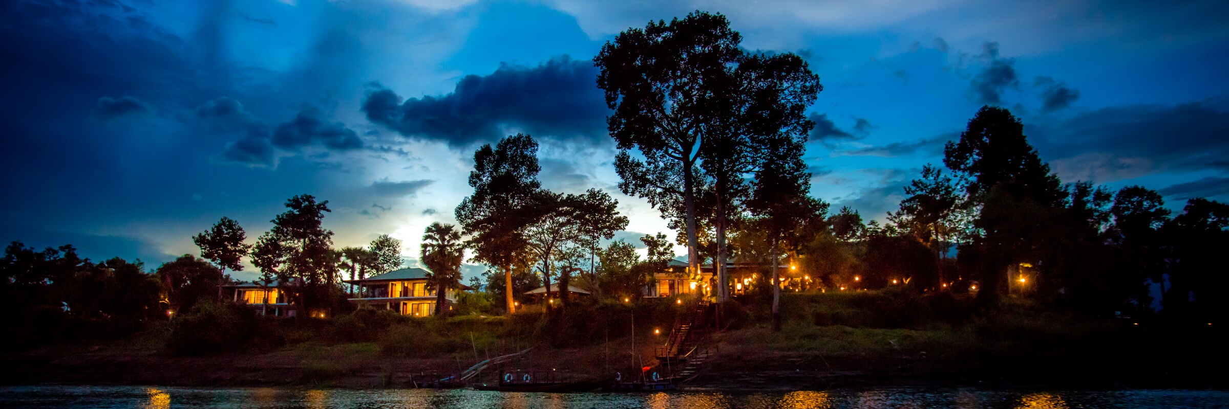 Eine wunderschoene Aussicht vom Mekong auf das River Resort Champasak bei Sonnenuntergang.