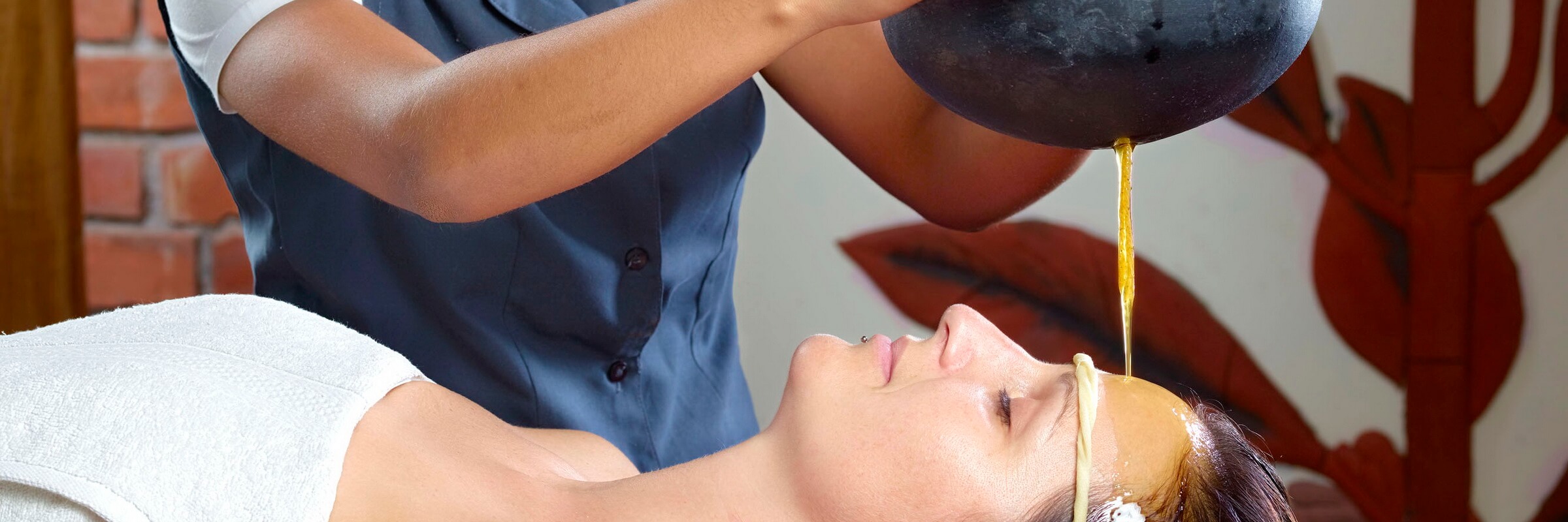Beim ayurvedischen Stirnguss Shirodhara lässt man warmes Öl über Stirn und Kopf fließen, um beide Gehirnhälften in Einklang zu bringen und den Geist zu entspannen.