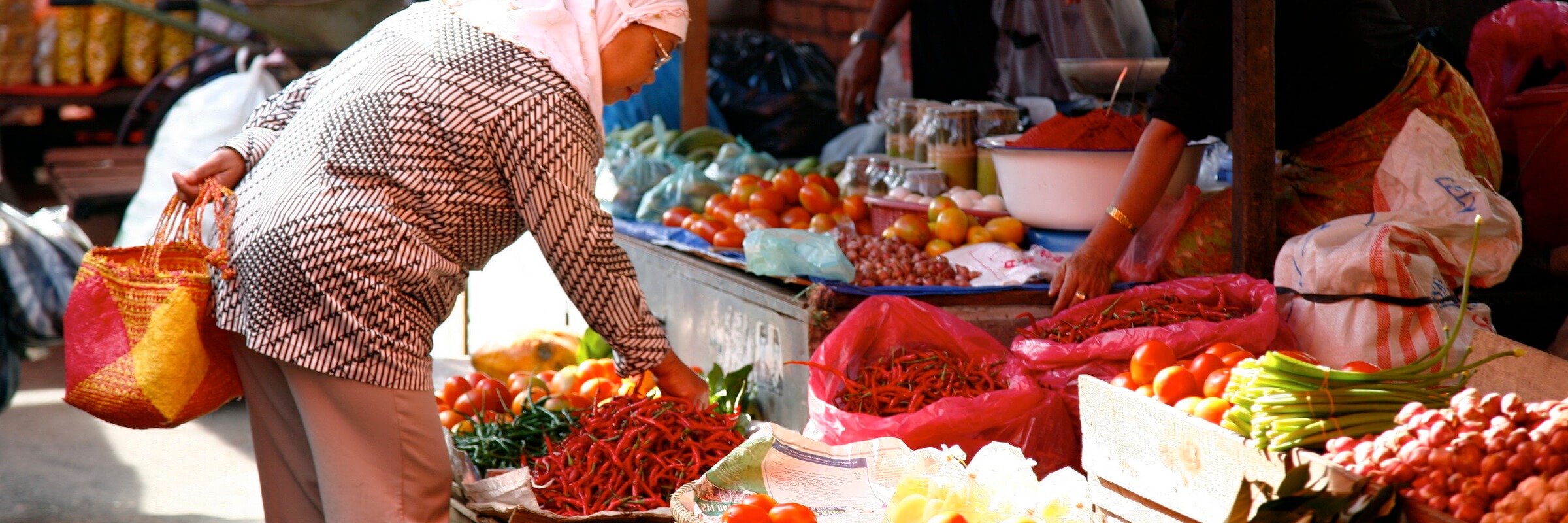 An einem bunten Markstand auf der indonesischen Insel Sumatra wird frisches Obst und Gemüse angeboten.