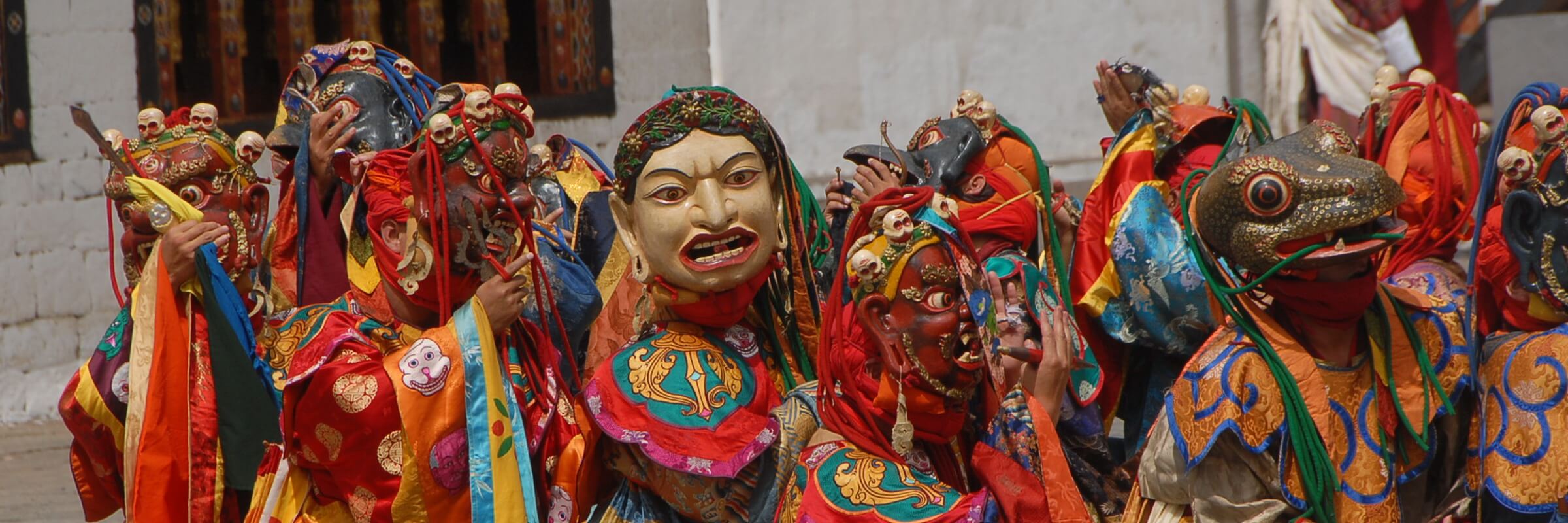 Maskentänzer mit traditionellen Gewändern und Masken bei der Darstellung eines spirituellen buthanesischen Tanzes.