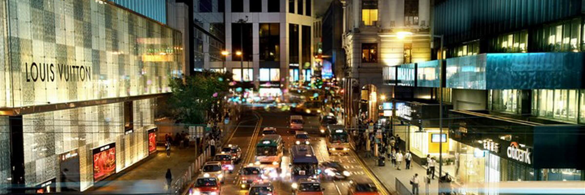 Einkaufsstraße mit Geschäften und Straßenverkehr im Zentrum von Hongkong.