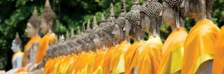 Entlang der Einfassungsmauer im Garten des Wat Yai Chai Mongkon in Ayutthaya sind zahlreiche Buddha-Statuen aufgereiht.