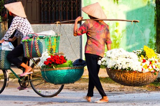 Blumenverkäuferinnen durchstreifen die Straßen im vietnamesischen Hanoi