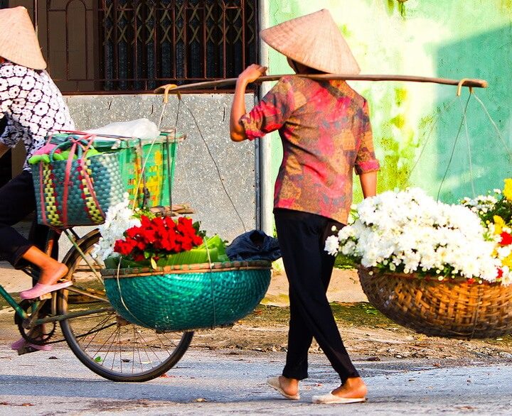 Blumenverkäuferinnen durchstreifen die Straßen im vietnamesischen Hanoi