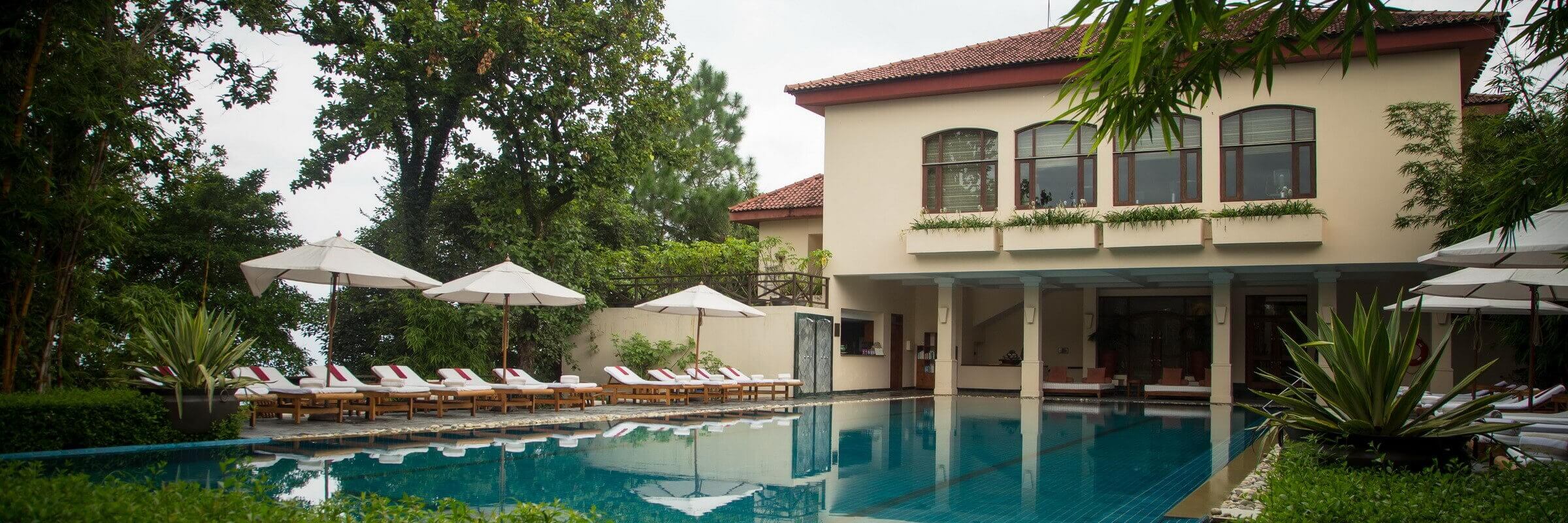 Der einladende Pool mit stilvollem Hauptgebäude des Ananda in the Himalayas