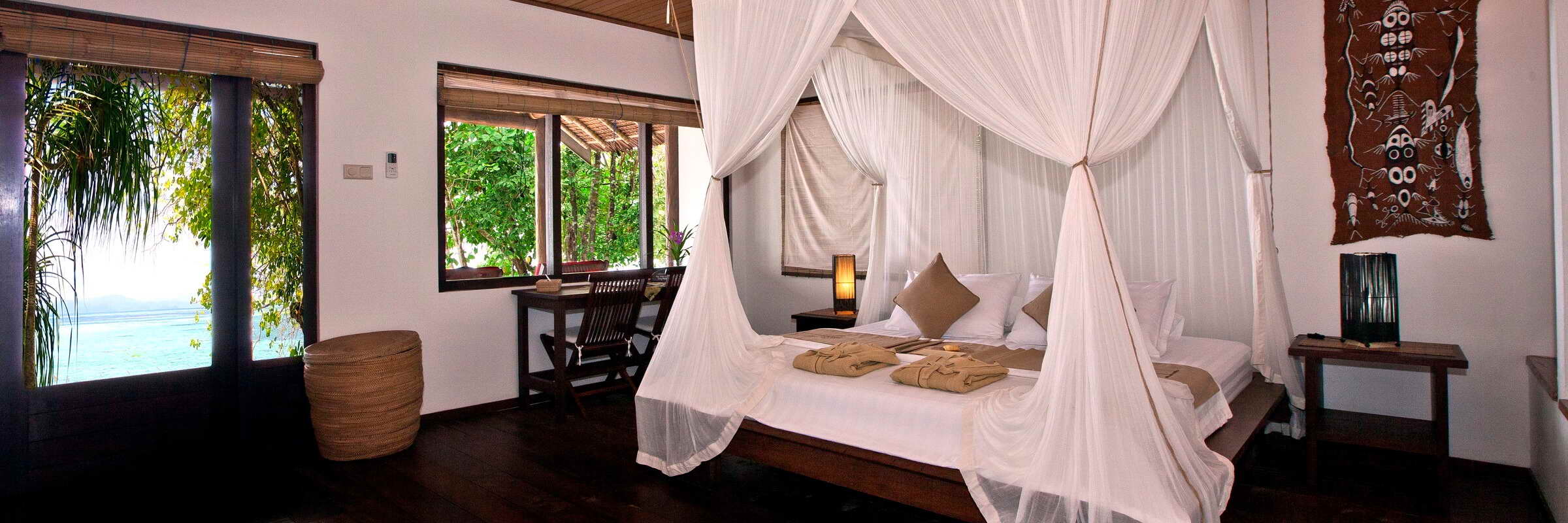 Ein exklusiver Sentani Strand-Bungalow des Sorido Bay Resorts in Raja Ampat, Indonesien. Der traditionelle Holz- und Stein-Bungalow liegt direkt im weißen Sand unter Palmen, mit Blick auf das türkisfarbene Meer und die Lagune.