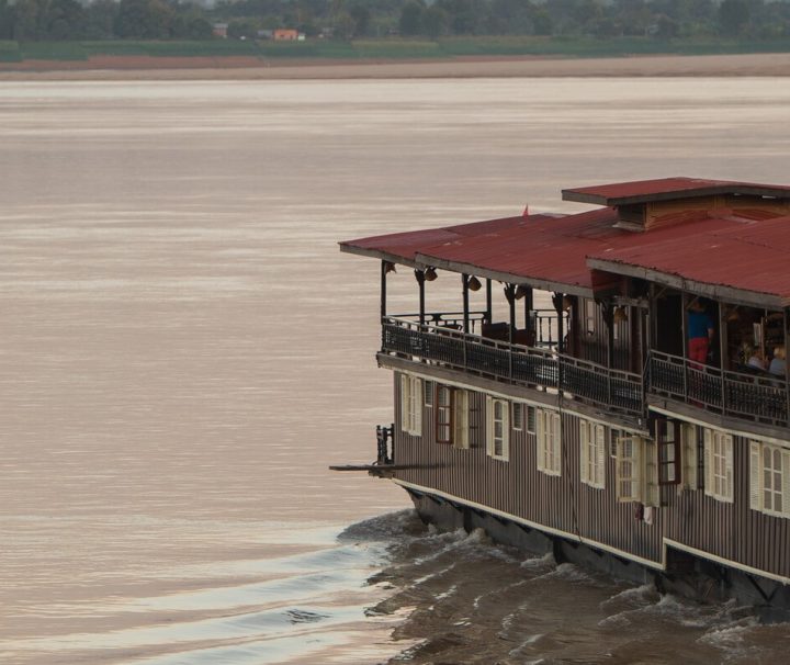 Auf einer Kreuzfahrt mit der Vat Phou können Gäste bei einem Sundowner in der Bar einen atemberaubenden Sonnenuntergang genießen.