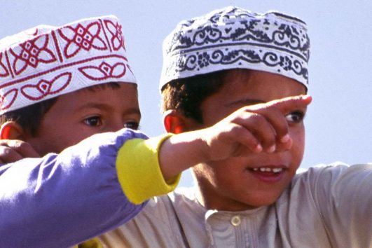 Zwei Jungen in traditioneller omanischer Kleidung, dem Kumma und Dishdasha.