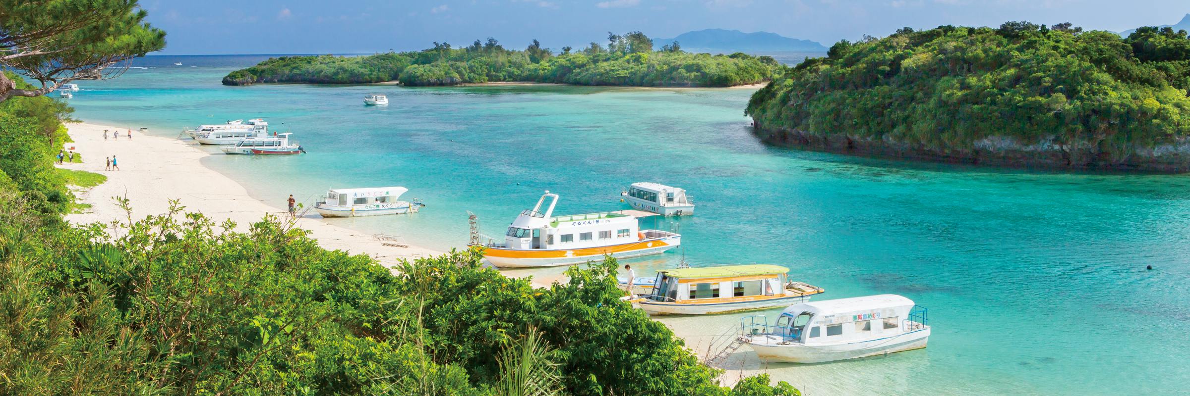 Ausflugsboote an einem Strand von Okinawa Die Präfektur Okinawa besteht aus 160 Inseln, wovon 47 bewohnt sind, viele lassen sich auf Ausflügen erkunden.