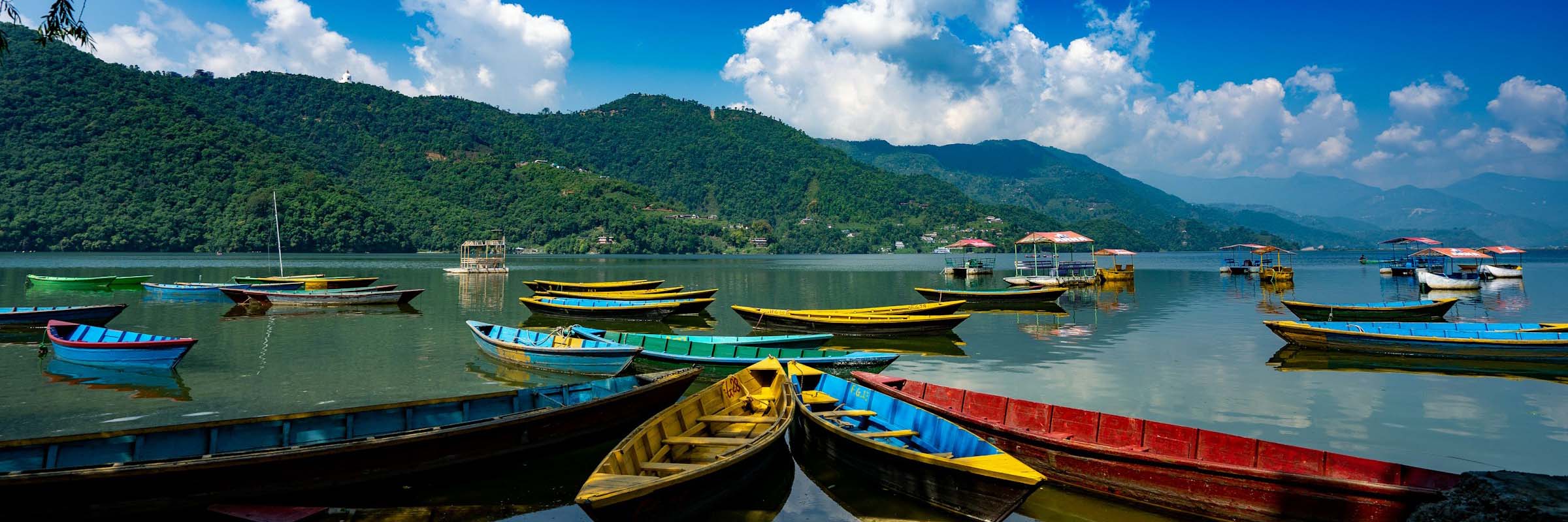 Bunte Boote warten auf Gäste am Pokhara See in Nepal