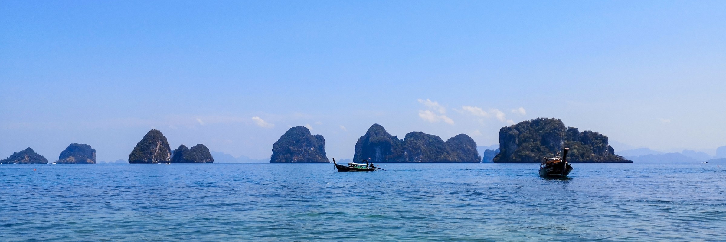 In der von Karstfelsen durchzogenen thailändischen Inselwelt sind die traditionellen Longtailboote ein gängiges Transportmittel.