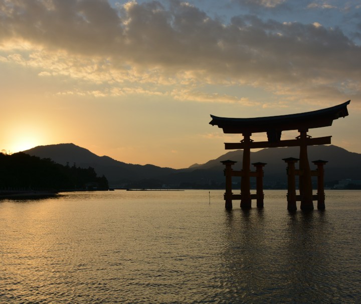 Sonnenuntergang am Torii des Itsukushima-Schrein auf der japanischen Schrein Insel Miyajima Das rote Torii auf der japanischen Schrein Insel Miyajima bildet den symbolischen Zugang zum Itsukushima Schrein der Teil des UNESCO-Weltkulturerbes ist.
