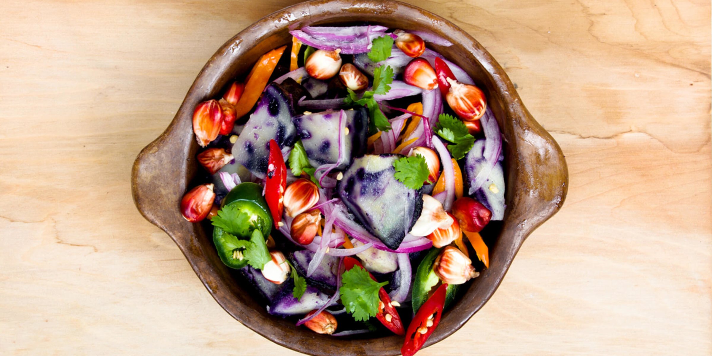 Gemischter Gemüsesalat mit lila Kartoffeln, roten Zwiebeln, frischem Koriander und roten Chilischoten