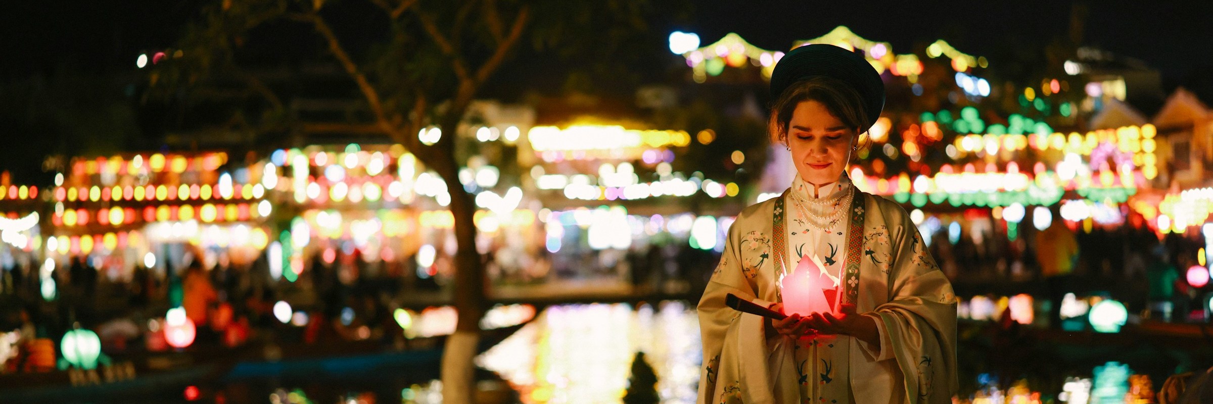 Frau in traditioneller vietnamesischer Kleidung am Ufer des Hoai-Flusses in Hội An