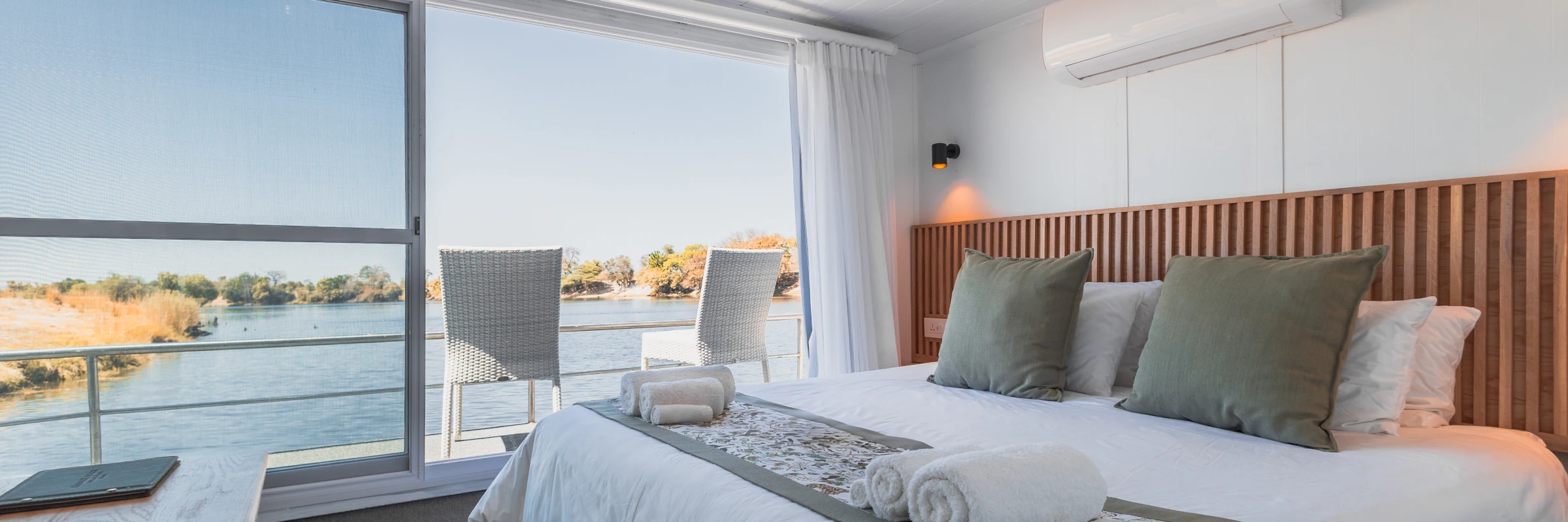 Modern eingerichtete Kabine auf der Chobe Princess mit Doppelbett und großer Panorama-Glasfront.