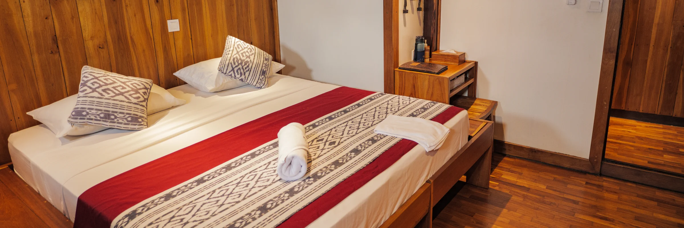 Stilvoll eingerichtete Doppelbett-Kabine mit edler Holzverkleidung an Bord eines Luxus-Tauchschiffs für Raja Ampat Reisen.