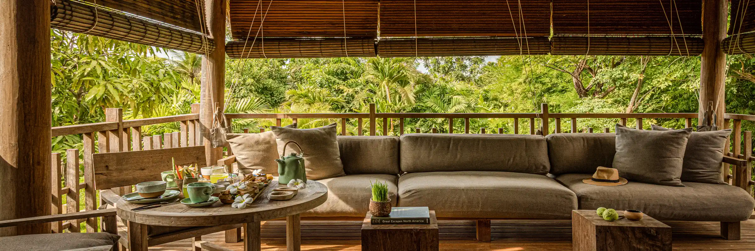 Gedeckter Frühstückstisch und gemütliche Lounge auf der Holzterrasse einer Villa im Zannier Phum Baitang.