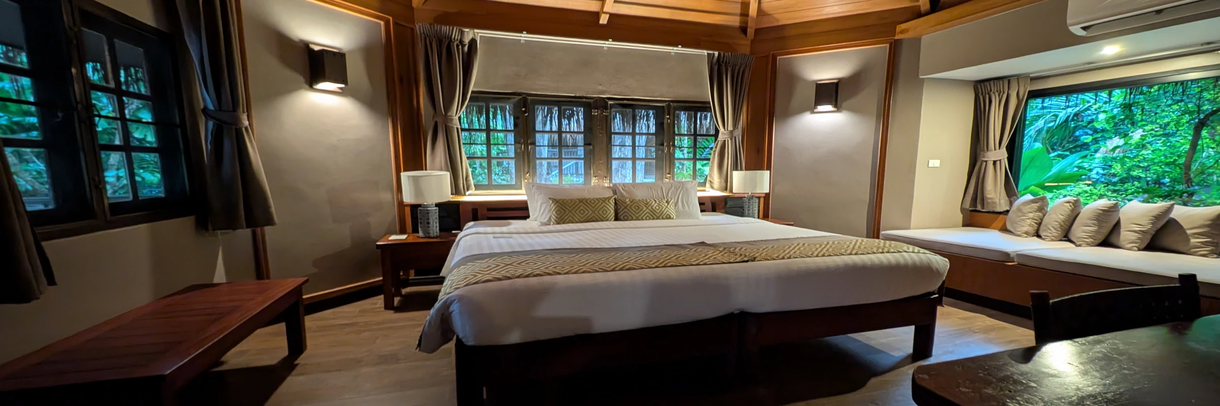 Gemütliche Innenansicht eines Dschungel-Bungalows im River Kwai Resotel mit großer Holzdecke und Dschungelblick