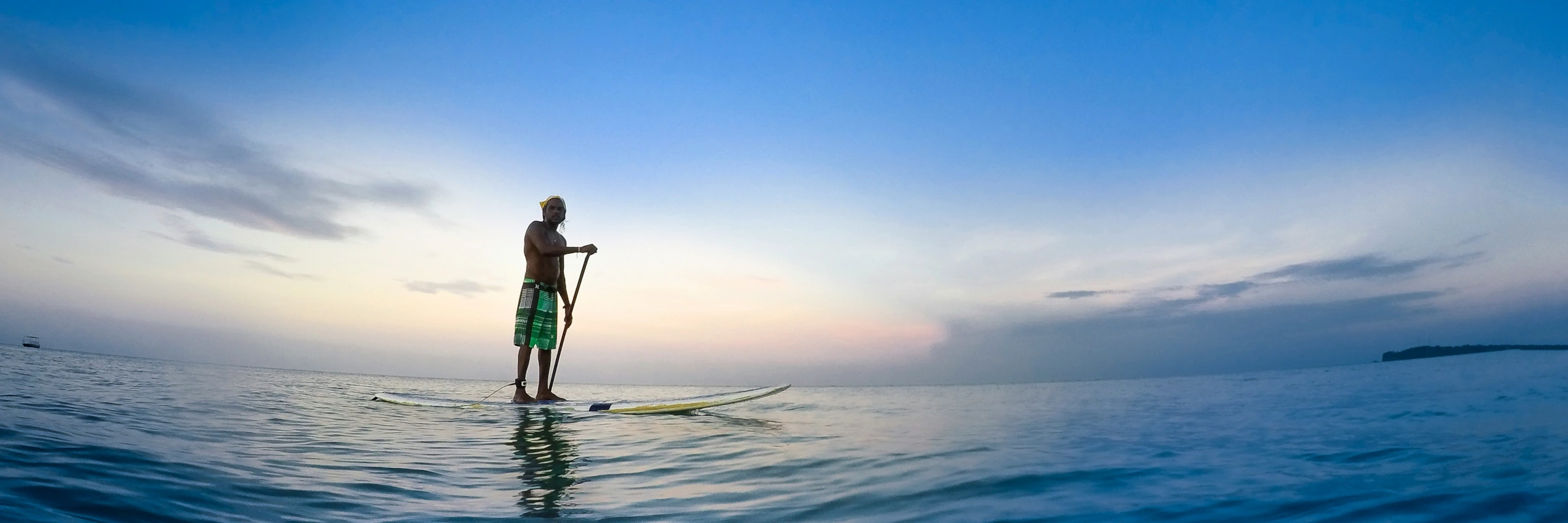 Ein Mann beim Stand-Up-Paddling auf ruhiger See vor der Küste Sri Lankas im sanften Abendlicht.